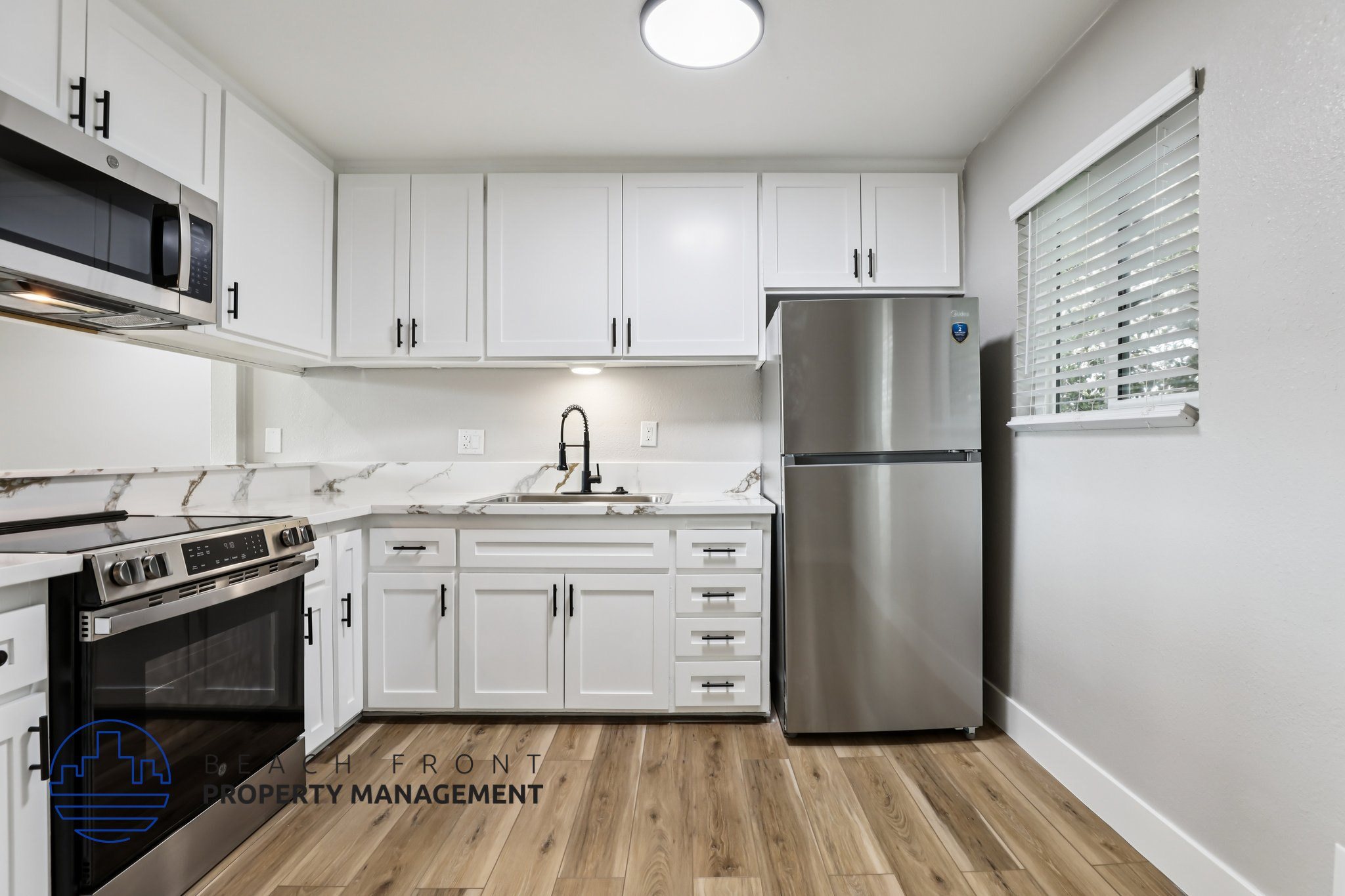 A modern kitchen with white cabinets and stainless steel appliances.